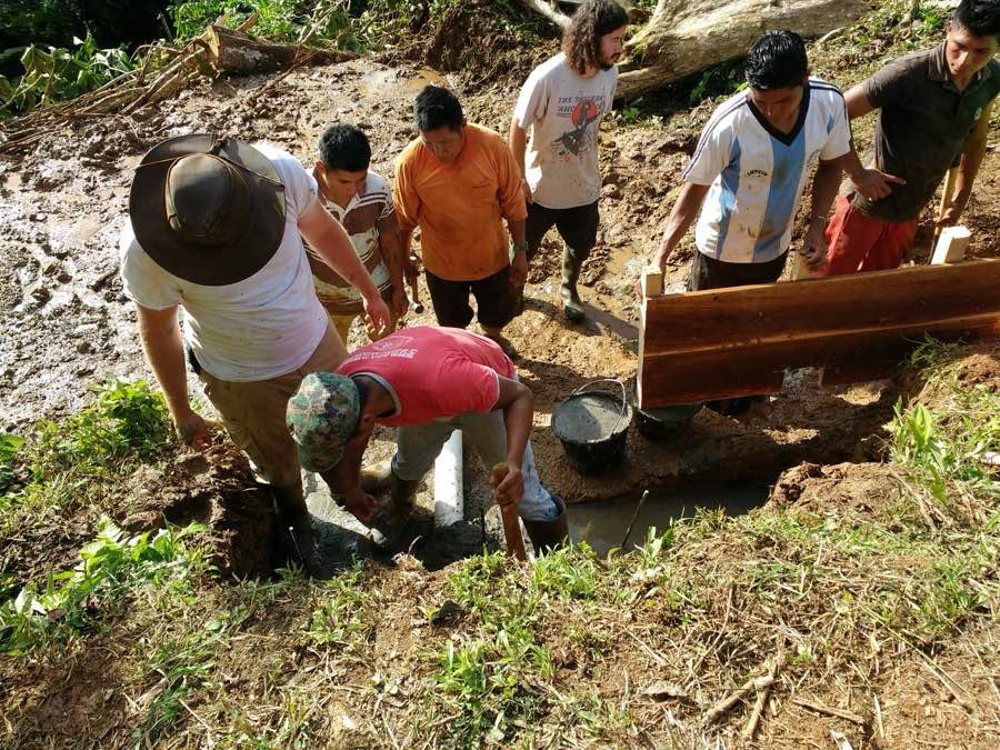 Community crew pouring concrete at a spring capture site in the Ecuadorian jungle